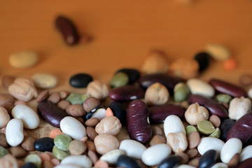 Different beans scattered on a wooden surface close-up. Naturel organic food background