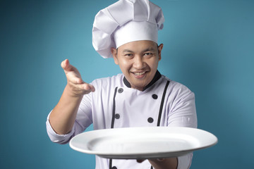 Asian Male Chef Shows Empty White Plate, Presenting Something, Copy Space
