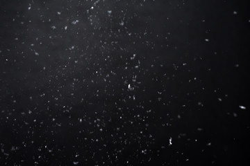 Falling  snow at night. Bokeh lights on black background, flying snowflakes in the air. Overlay...