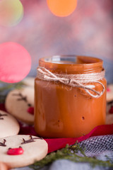 Christmas cookies with homemade salted caramel on a wooden background, neon lights, cinnamon sticks.