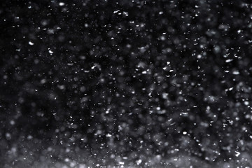 Falling  snow at night. Bokeh lights on black background, flying snowflakes in the air. Overlay texture. Snowstorm