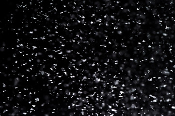 Falling  snow at night. Bokeh lights on black background, flying snowflakes in the air. Overlay texture. Snowstorm