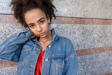 Outdoors Leisure. Young stylish african girl in denim jacket standing isolated on wall touching face smiling cute close-up