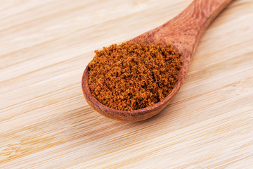 Spoon full of dark brown sugar  on a wooden background