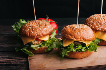 three homemade hamburgers with meat, cheese, lettuce and tomatoes