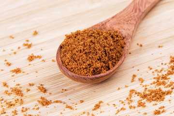 Spoon full of dark brown sugar  on a wooden background