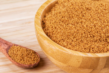 Bowl full of dark light sugar on a wooden background