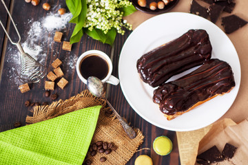 Fresh homemade eclairs with chocolate on the kitchen table. French pastries.