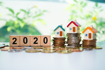 Wooden block year 2020 and mini house on stack coins using as business and financial concept