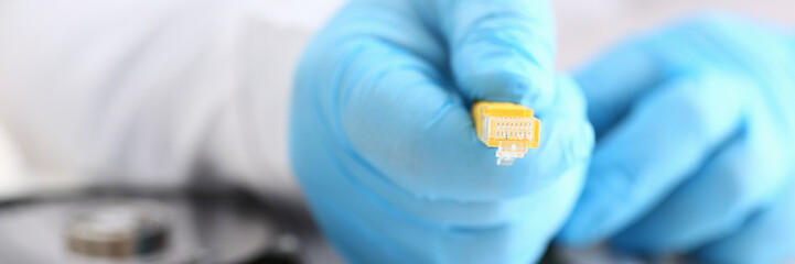 male hand in blue protective gloves holds a network connector