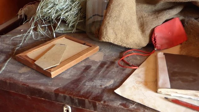 Pan view of dusty table with retro objects - notepad, pencil, photo frame, some old fabric and case.