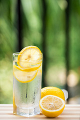 A glass of lemonade and cut lemon on a red table