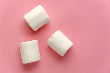 Three white marshmallows on millennial pink background. Minimal flat lay. Pink mood concept. Copy space