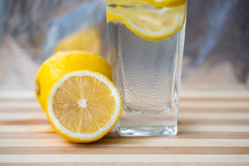 A glass of lemonade and cut lemon on a red table