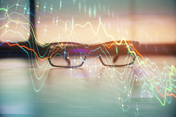 Financial graph hologram with glasses on the table background. Concept of business. Double exposure.
