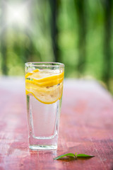 A glass of lemonade and cut lemon on a red table