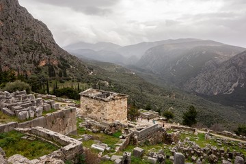 Fototapeta na wymiar The landscape of ancient Delphi in Greece with Treasury of Athenians and cloudy weather