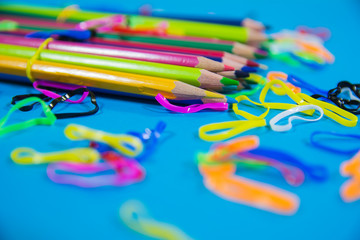 set of random color pencils with random color rubber bands on blue background