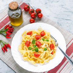Spaghetti with cherry tomatoes and mint on a white plate, top view