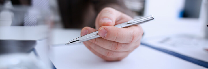 Male arm in suit and tie hold silver pen