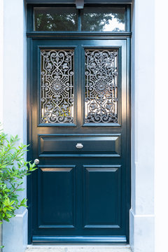Dark blue painted wooden door with intricate ornate window grate and silver colored door handle