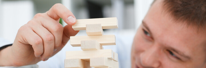 Businessman plays in a strategy of jenga hand