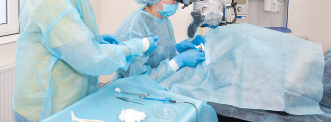 Nurse giving a tool to a doctor during surgery. Hands of doctors during hospital surgery. Ear...