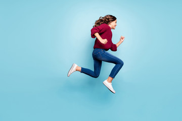 Fototapeta na wymiar Full length body size photo of curly wavy cheerful trendy preteen wearing jeans denim burgundy sweater running jumping towards shopping mall isolated vivid blue color background