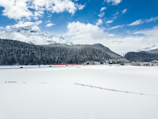 Snow field with forest and railway line at the background in winter