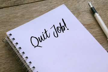 Pen and notebook written with Quit Job! on wooden background.
