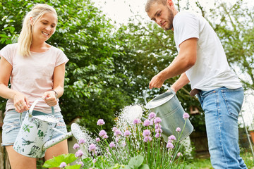 Junges Paar gießt Blumen zusammen im Garten