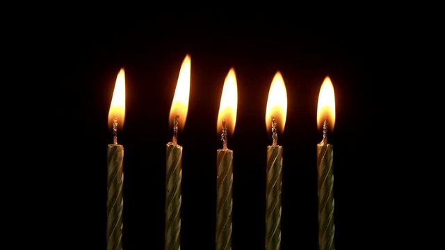 Golden birthday candles burning on black background