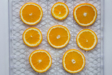 Cutted orange on dehydrator grid on white background