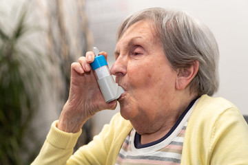 Fototapeta na wymiar Old woman using an asthma inhaler