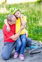 Fototapeta premium Father looks at the wound of his daughter, who fell from a bicycle