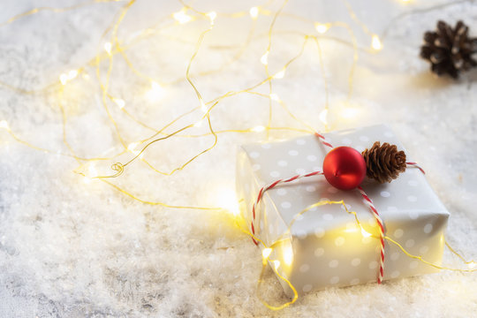 Christmas festive background with present box and glowing garland on the snow. Greeting festive image.