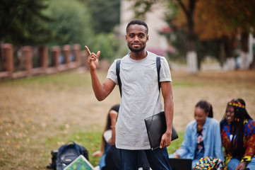 Group of five african college students spending time together on campus at university yard. Black...