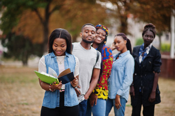 Row of group five african college students spending time together on campus at university yard. Black afro friends studying. Education theme.