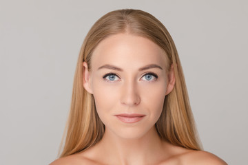 Medium close-up portrait of beautiful young European woman isolated at white studio background. Charming smiling naked female with long blonde hair looking at camera having positive emotion