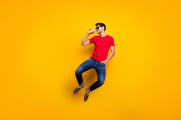Fototapeta na wymiar Full length photo of cheerful charismatic guy jump drink espresso take away cup enjoy free spring time wear red t-shirt sneakers isolated yellow color background