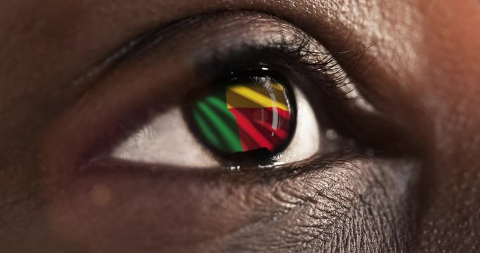 Woman black eye in close up with the flag of Benin in iris with wind motion. video concept