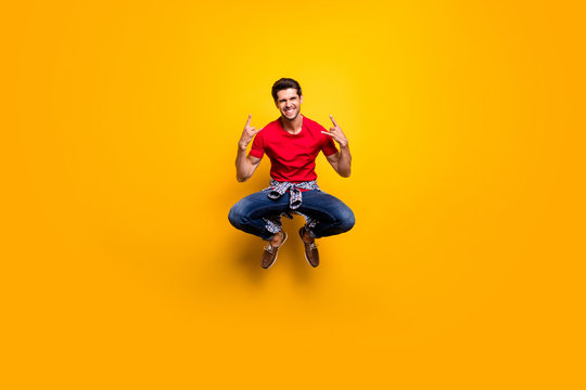 Full length photo of cheerful excited guy panker jump visit concert show horns symbol wear bred t-shirt sneakers isolated over vivid color background