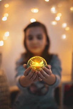 Ni&ntilde;a en navidad con bola m&aacute;gica y luces por las fiestas de la natividad