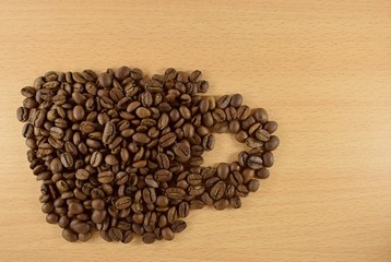 coffee beans laid out on a wooden surface in the form of a cup
