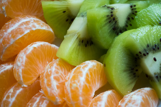 Fondo de ensalada de frutas. Trozos de kiwi y gajos de mandarina. Macro.