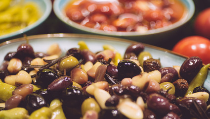 Olives and peppers marinated in oil. Pickled olives in a bowl on the table. Vegetarian snack