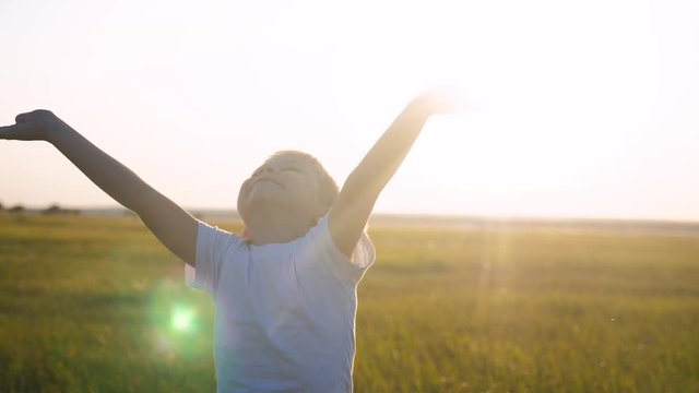 small child hands drawn to heaven concept happy family religion. little boy closed his lifestyle eyes spread his arms to the sides on the nature in the park at sunset slow motion video