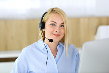 Call center. Blonde business woman sitting in headset at customer service office. Concept of...