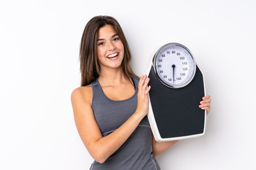 Teenager Brazilian girl holding a scale over isolated white background with weighing machine