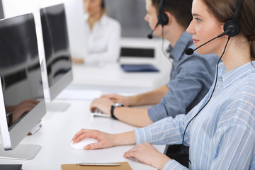 Call center. Group of casual dressed operators at work. Focus on business woman in headset at customer service office. Telesales in business